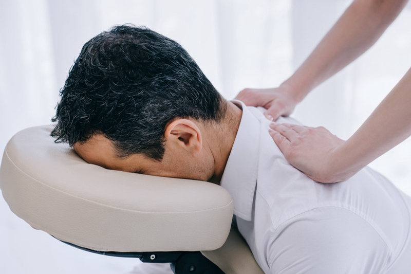 Terapeuta a realizar massagem em cadeira a um colaborador